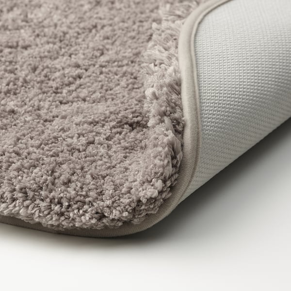 Close-up of soft, plush, beige bath mat with textured surface and non-slip backing.