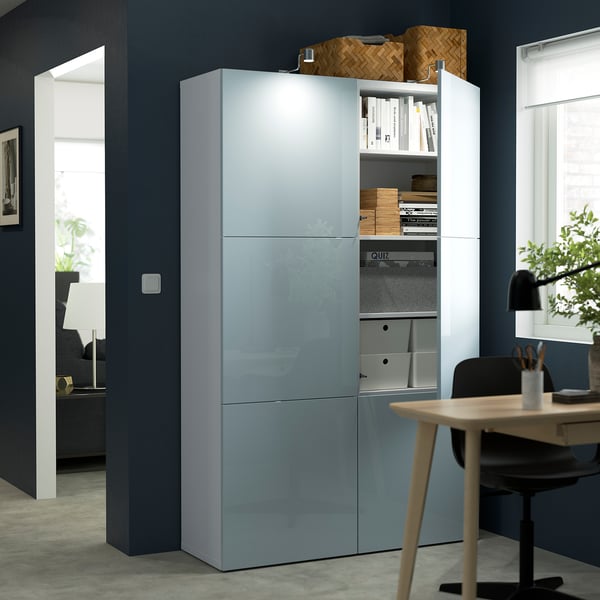 Modern storage unit with glass doors showcasing organised items. Includes shelves for books and boxes. The unit is integrated with office furniture.