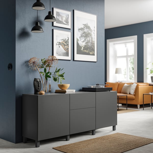Modern living room with dark grey BESTÅ storage unit, two pendant lights, framed photos, and orange sofa.