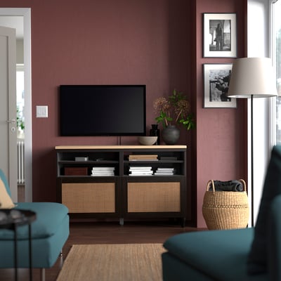 Modern living room: flat-screen tv on wooden stand, blue sofa, large wicker basket, purple walls,.