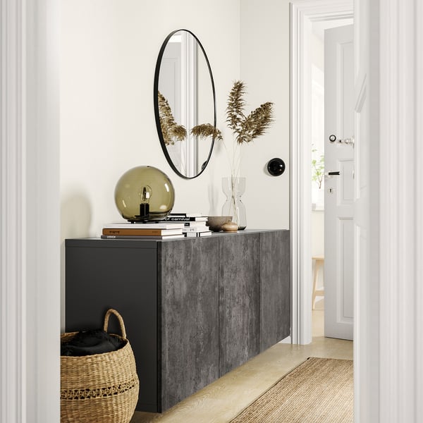 Modern entryway with BESTÅ grey storage unit, round mirror, lamp, flowers, basket, and white doors.