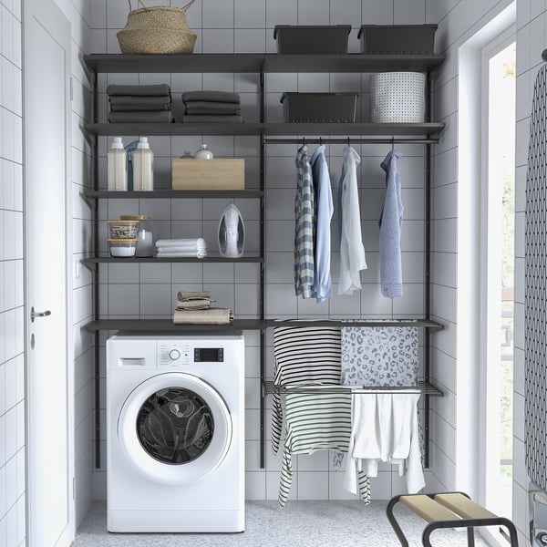 Modern laundry: white washer, grey shelves, organised with towels & detergents, space-maximizing setup.