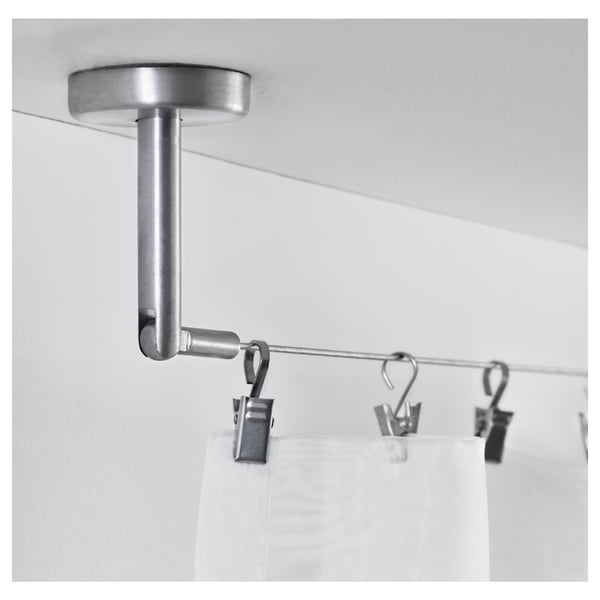 A silver ceiling-mounted curtain rod with hooks and clips, supporting white curtains, demonstrating its use for hanging and organising curtains.