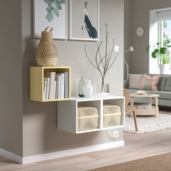 Modern living room with EKET cabinet, books, vases, art, sofa, and wooden table.
