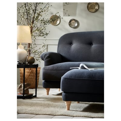 Cosy living room with dark blue sofa, lamp, vase, and candles.