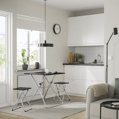 Modern kitchen with white cabinets, black metal table & stool, large window, compact for storage, stylish pendant light.