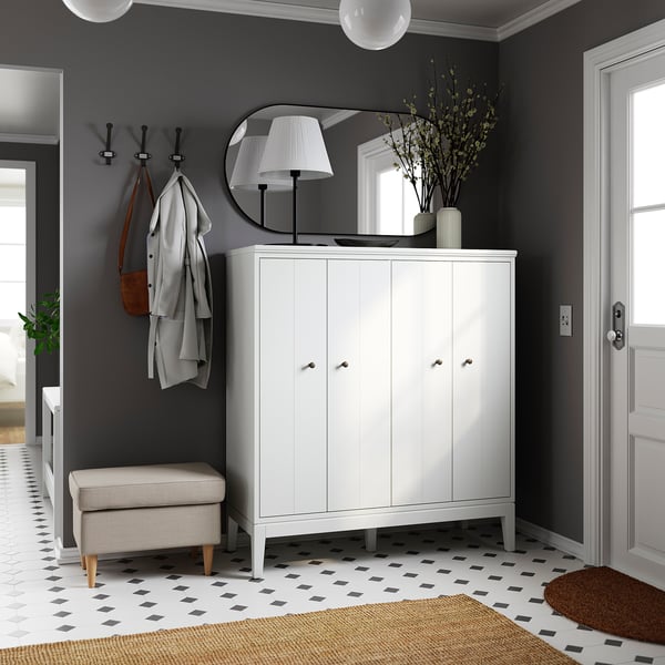 Modern entryway with IDANÄS white cabinet, round mirror, hanging coats, lamp, plant, chequered floor, and rug.