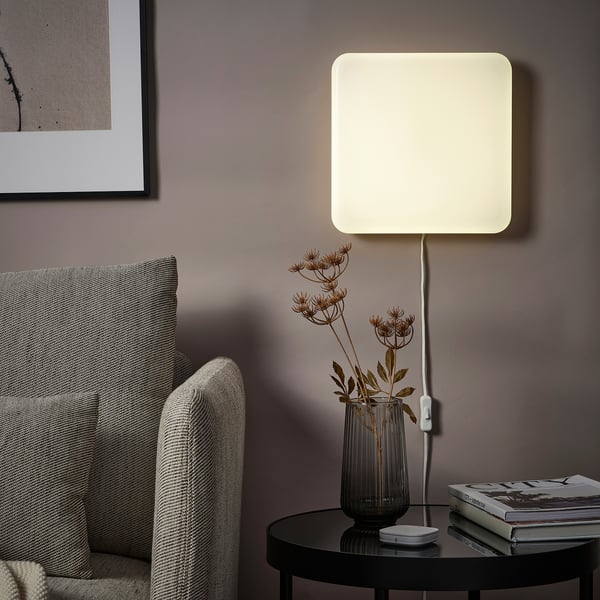 Modern living room with gray couch, smart light, and green vase on table against dark gray wall.
