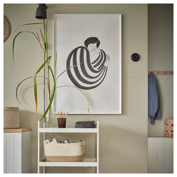 Accessories on wall: picture frame with black art, storage rack with basket and plants.