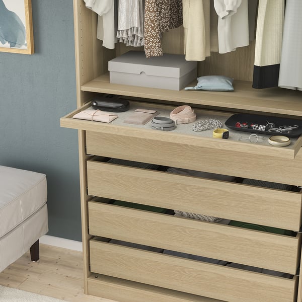 Wooden dresser with pull-out tray holding wallets, belts, and jewellery; soft felt mat and shallow drawers below.