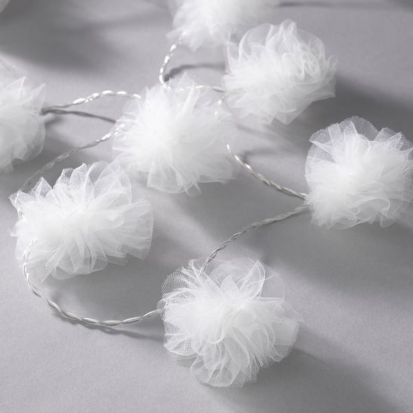 String lights with multiple white mesh pom-poms creating a festive ambiance.