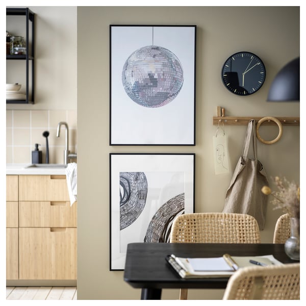Kitchen with wooden cabinets, black tap, art wall, LOMVIKEN frames, clock, hooks.