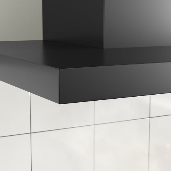 Black modern kitchen hood with sleek lines and led lighting mounted on a tiled wall.