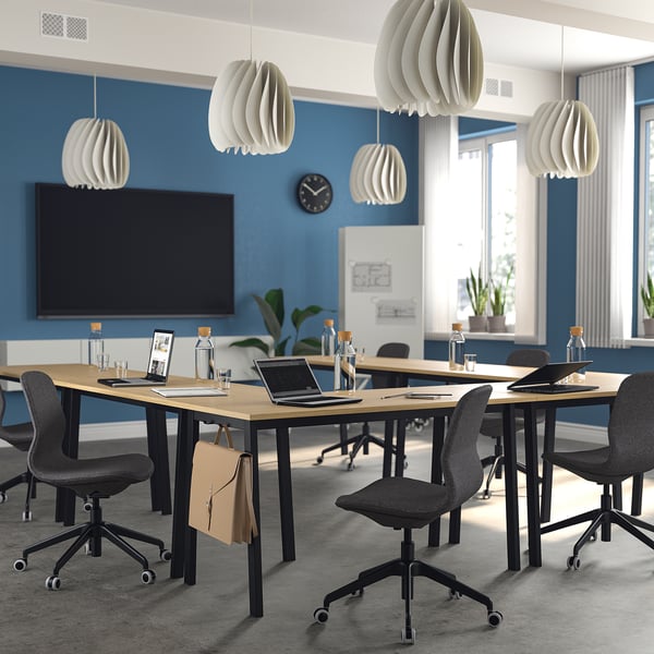 Modern conference room with MITTZON tables, grey chairs, blue walls, and a large screen.
