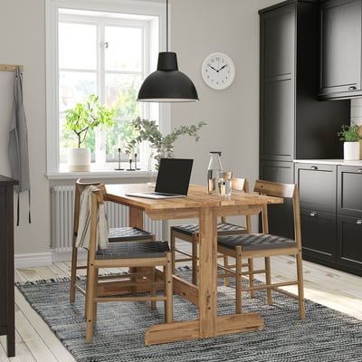 NACKANÄS dining table, light brown acacia, seats 4-6, rustic design, under black lamp.