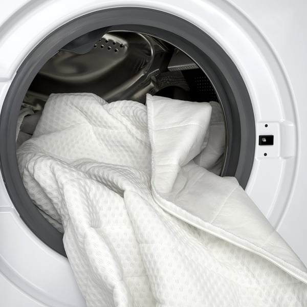 White dryer with mattress pad inside, showcasing machine washable cover.