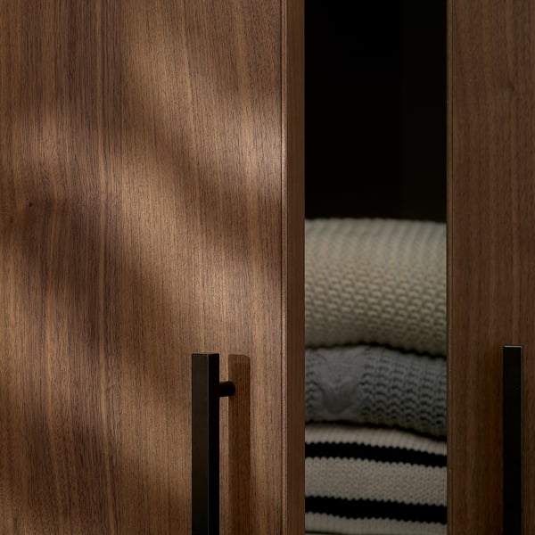 Wooden cabinet with sleek, dark handles showing folded blankets inside, highlighting quality and organisation.
