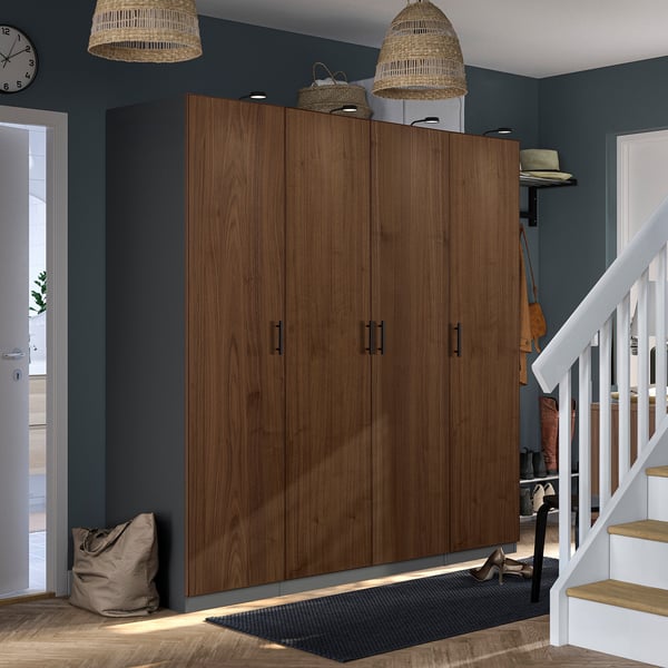 Large wooden PAX wardrobe with dark finishes between staircase and door, with wicker lamps above.