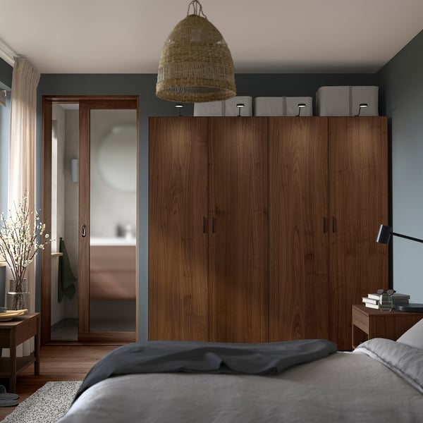 Modern bedroom with large wooden wardrobe, cosy bed, pendant lamp, and bedside table.