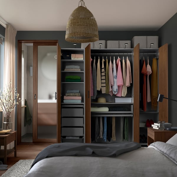 Organised bedroom closet with clothes, shelves, drawers, lamp, and flowers.