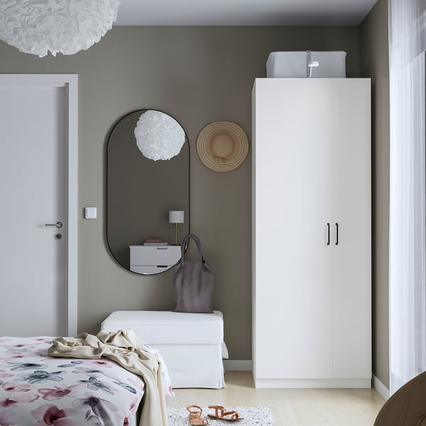 Modern bedroom with a white corner PAX wardrobe, large mirror, and floral bedspread.