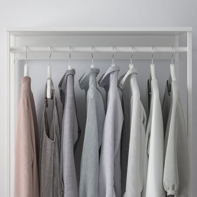 A closet with a hanging rod showcasing various shirts and garments in different shades of grey and others, organised neatly.