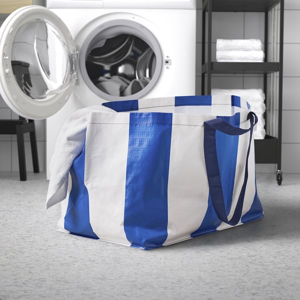 Blue and white laundry bag near dryer.