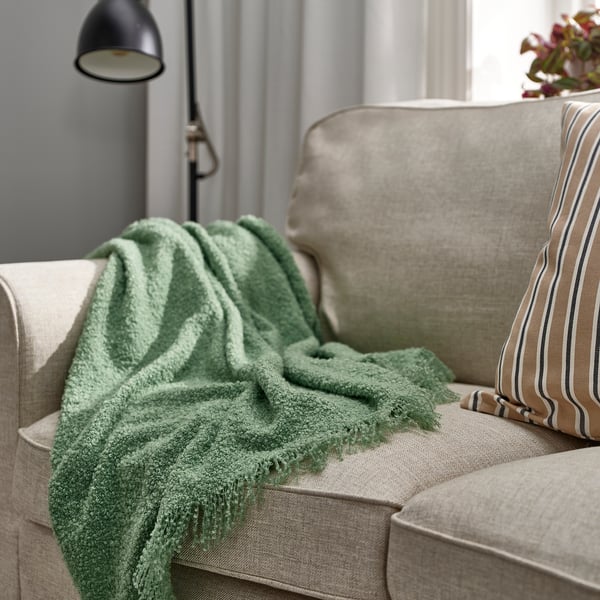 Green SANDBRODD recycled polyester throw on couch.