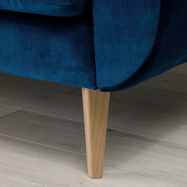 A close-up of a blue velvet sofas leg, showcasing the quality materials and design.
