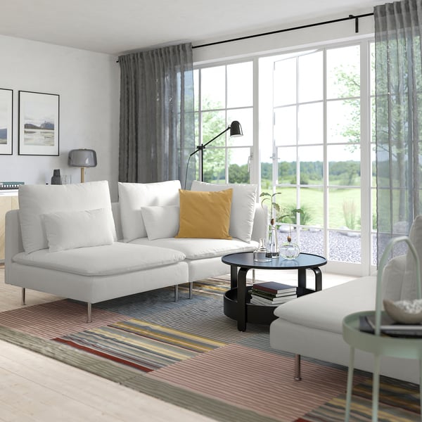 Modern living room with SÖDERHAMN white sofa, yellow pillow, striped rug, black coffee table, lamp, and large windows with curtains.