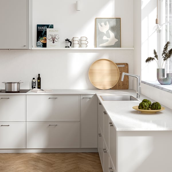 Modern kitchen with large recycled glass wall panel, sleek countertop, wooden tray, and artichokes.