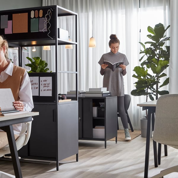 Two people in modern office with TROTTEN desks and chairs.