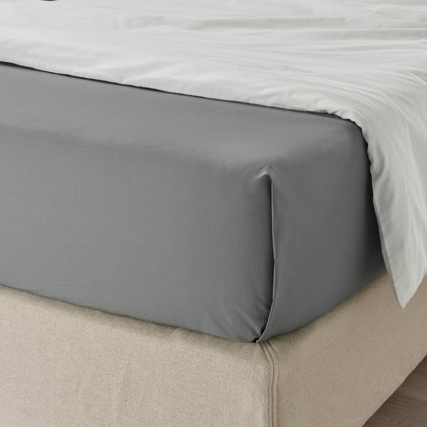 A bed with grey fitted sheet, neatly tucked, showcasing a high thread count, breathable, moisture-absorbing fabric.