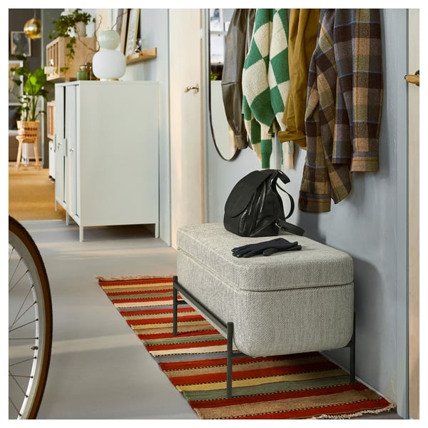 Indoor space with VALTORP bench, striped rug, backpack, blue wall, jackets, and storage unit.