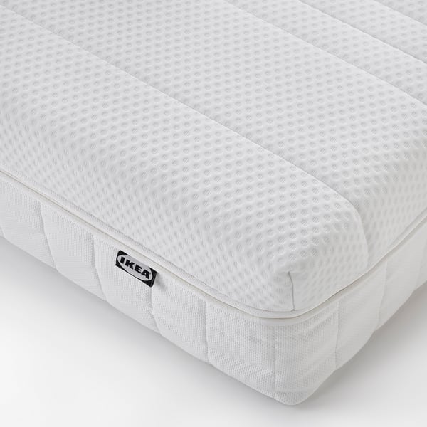 Närbild av IKEA-madrass som visar upp den quiltade vita ytan och den fasta strukturen, vilket indikerar komfort och stöd av hög kvalitet.
