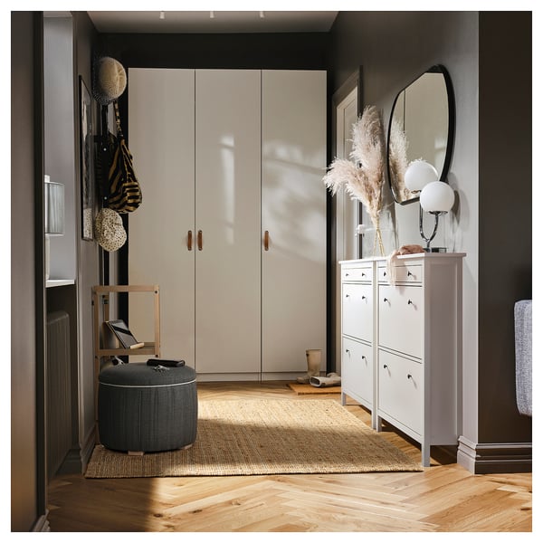 Modern entré med vitt skåp, spegelhylla, förvaringsmöbel, beige matta, grå ottoman och naturlig inredning.