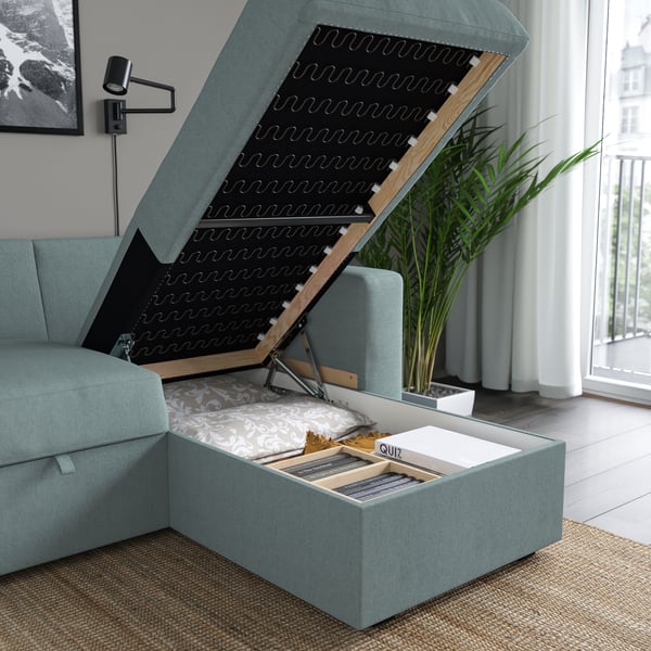 Modern bäddsoffa med öppen förvaring; Kuddar och brädspel synliga inuti.