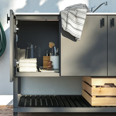 Modernt utomhusköksskåp med mjukstängande gångjärn, förvaringsredskap och handdukar, redo för matlagning utomhus.