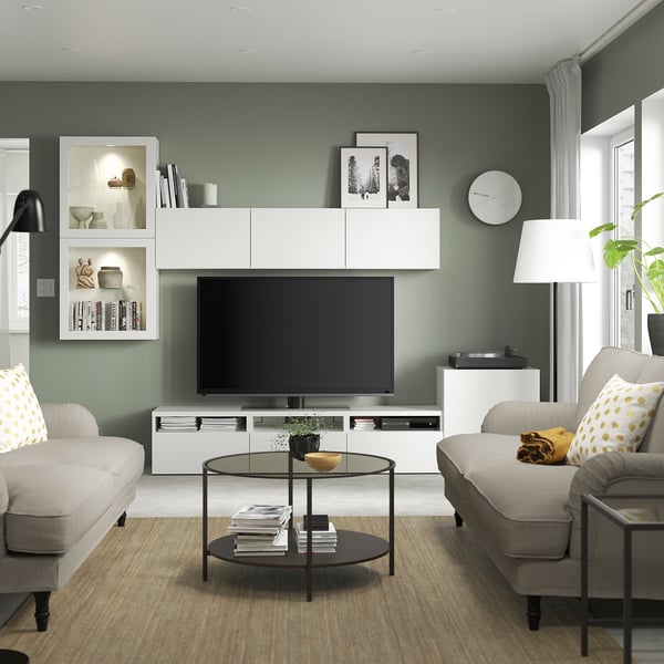 Modernt vardagsrum med salvia väggar, BESTÅ tv-enhet, grå soffa, lampa, soffbord med böcker och stort fönster; Mysigt och snyggt.
