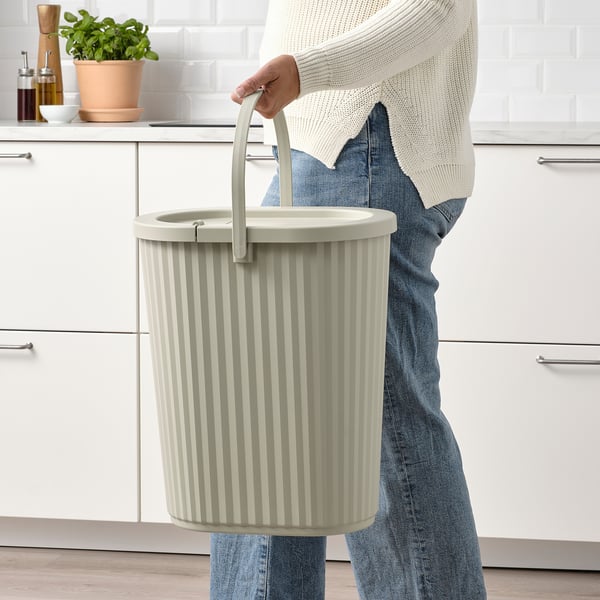 Person som håller i soptunnan DAMMÄNG med handtag, perfekt för återvinning av glas, plast och papper, med lock för att gömma avfall, stående i ett modernt kök.