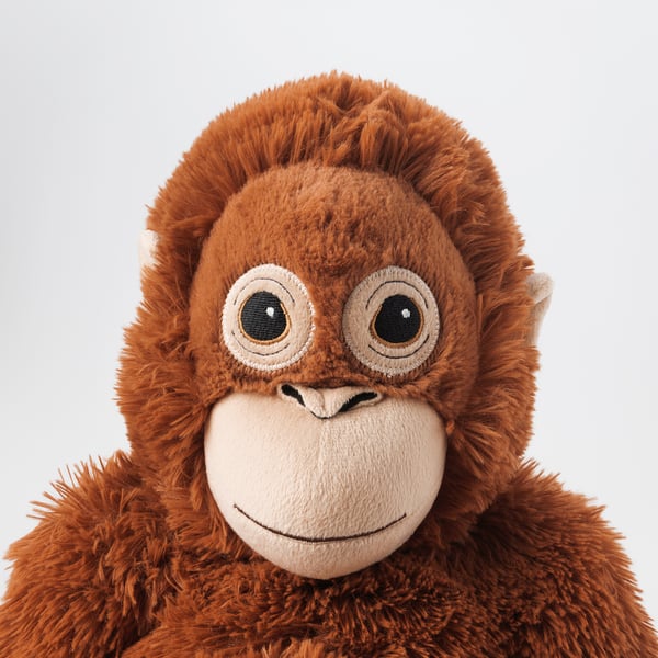Plyschig orangutangleksak, mjukt, detaljerat ansikte, stora ögon, vänligt leende, tillverkad av polyester.