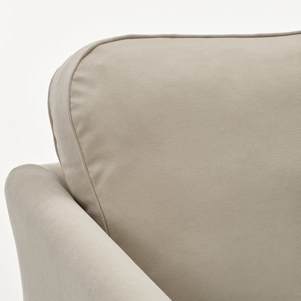 Närbild på en modern, beige soffa med mjuk, slät klädsel och svängda armstöd.