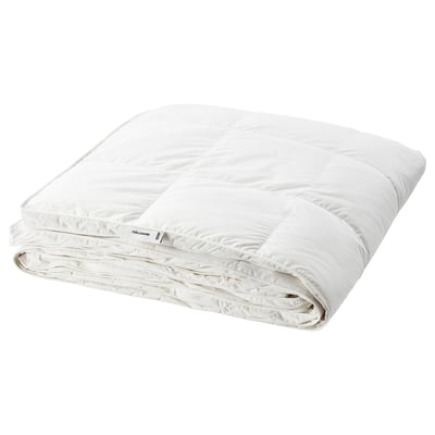 Ett vitt fjällräventäcke, tjockt och fluffigt, snyggt vikt. Den är tillverkad i 100% bomull med dun- och fjäderfyllning och ger extra värme.
