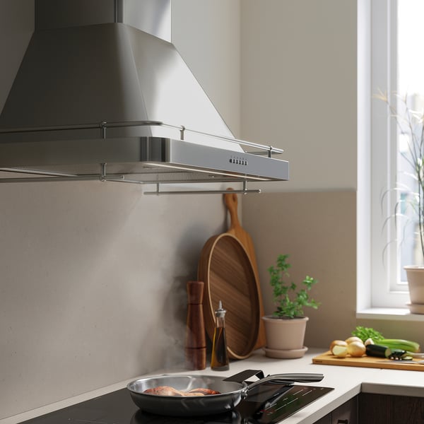 Modernt kök med rostfri FÖLJANDE fläkt, led-lampor och kokkärl.