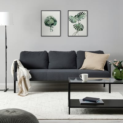 Modernt vardagsrum med soffan GLOSTAD, botaniska tryck, soffbord, lampa och matta.