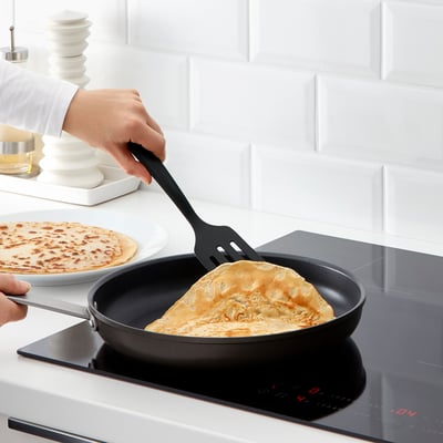 Person som lagar pannkakor med GNARP-redskap och spatel på en non-stick stekpanna.
