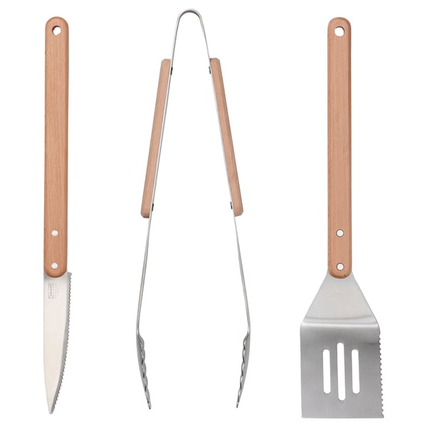 Tre grillverktyg: kniv, tång och stekspade med trähandtag, visas sida vid sida.