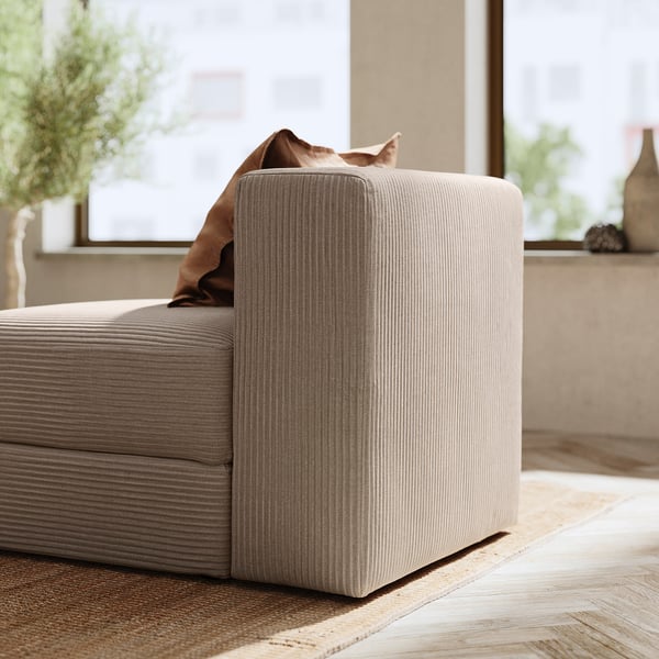 Modern beige modulär soffhörna med kuddar, mjuk textur och rena linjer. Perfekt för komfort och stil.