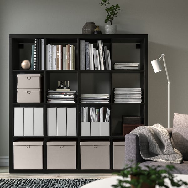 Svart KALLAX bokhylla med hyllplan, stol och lampa.