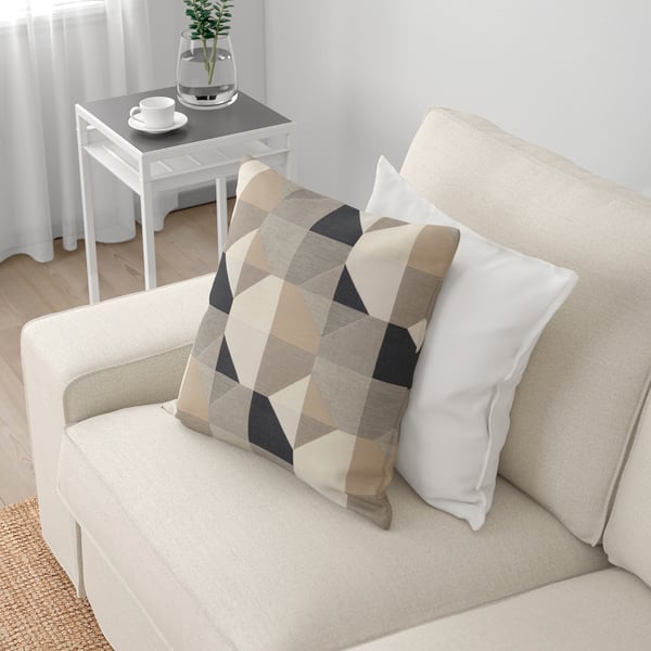 Beige soffa med geometriska kuddar i ett mysigt vardagsrum.